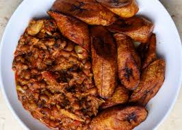An image of a finished, well cooked and garnished serving of beans, fried plantain with a dash of gari