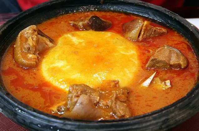 An image of a serving of fufu, light soup and goat meat
